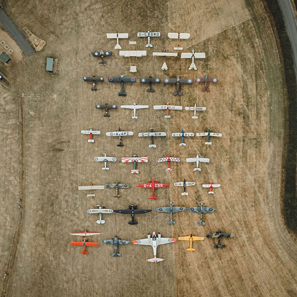 Aerial view of vintage aircraft arranged on a grass airfield