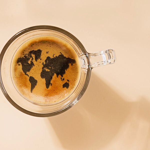 A cup of coffee with a foamy top topped with the map of the world.
