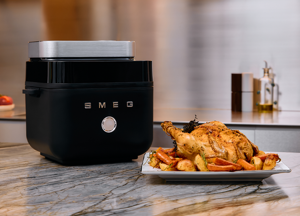 SMEG air fryer in black finish styled with gourmet salmon and herbs in a contemporary kitchen