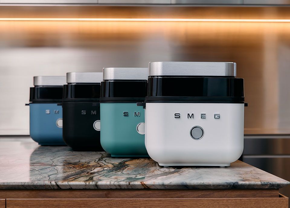 Smeg white air fryer on a countertop in a modern kitchen with wood cabinets, neutral tones and copper appliances