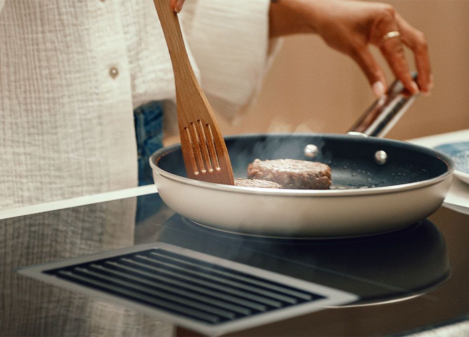 Woman cooking burger patties on a Classic HOBD cooktop