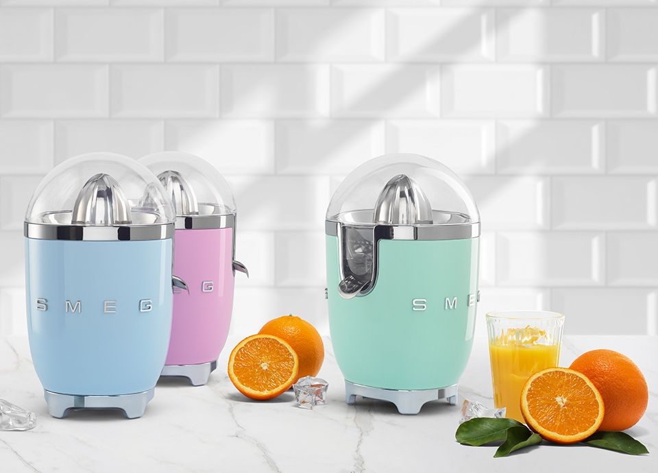 Trois Presse-agrumes CJF11 rose, bleu azur et vert d'eau sur un meuble de cuisine.