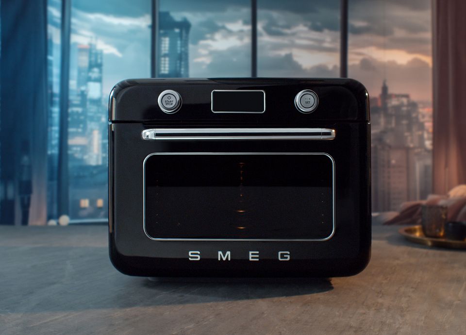 Forno combinato a vapore SMEG nero posizionato su una superficie in un ambiente interno.