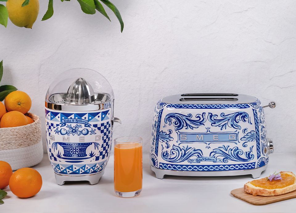 Un presse-agrumes et un toaster Blu Mediterraneo en collaboration avec Dolce&Gabbana sur une table blanche.