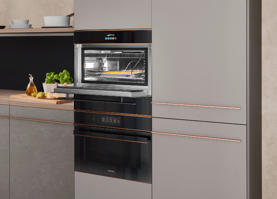 Cellule de refroidissement noire Smeg de l'esthétique Dolce Still Novo dans un cuisine contemporaine aux meubles gris et cuivre.