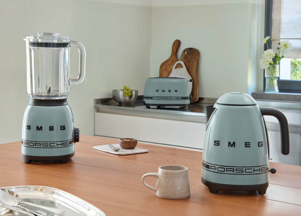 Ensemble de petit électroménager Porsche x SMEG de la collection Vert Ombre. Bouilloire, blender et grille-pain posés sur une table dans une cuisine.