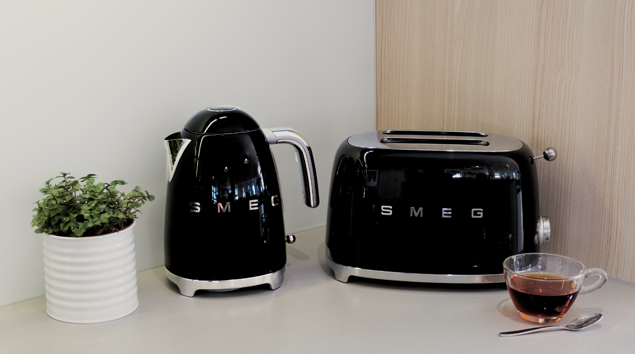 Ensemble petit-déjeuner SMEG bouilloire noire et grille-pain noir sur un plan de travail.