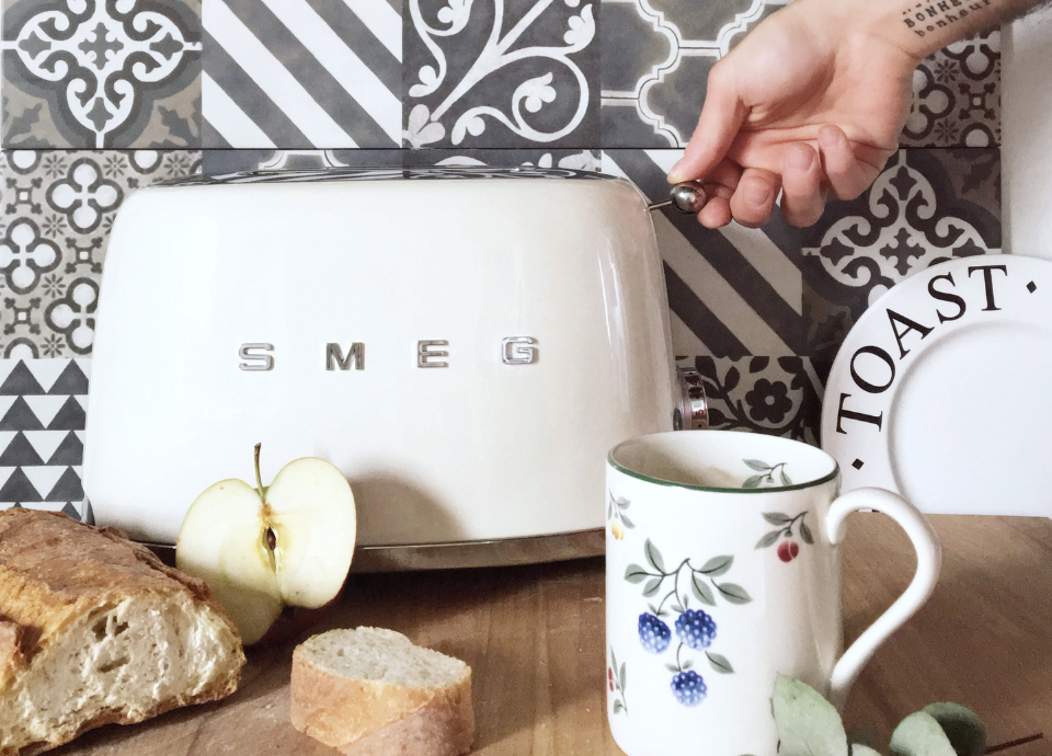 Grille-pain 2 tranches Smeg crème avec logo Smeg en lettres argentées dans une cuisine.