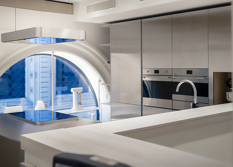 Scorcio del negozio SMEG Store Bologna, in esposizione piano cottura e cappa d'aspirazione sospesa della collezione ISOLA, forni della collezzione Classica e