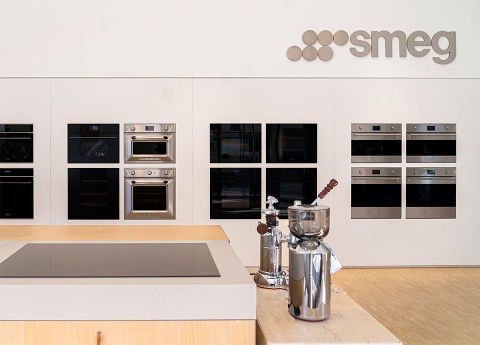Area espositiva interna dello SMEG Store Milano con forni e piani cottura