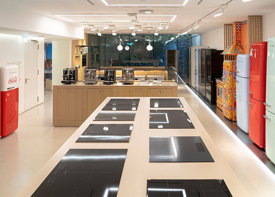 Area espositiva interna dello SMEG Store Milano con piani cottura, frigoriferi e cucine da libera installazione