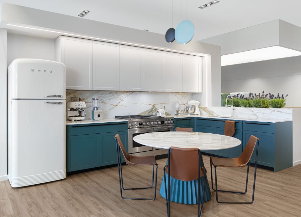 Composizione con cucina inox da libera installazione, frigorifero bianco e tavolo tondo con 4 sedie