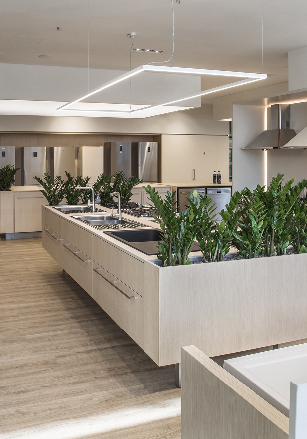 Area espositiva dello SMEG Store Reggio Emilia con una selezione di grandi elettrodomestici da incasso e a libera installazionee. In primo piano un'isola espositiva con lavelli e piani cottura; sullo sfondo sono esposti frigoriferi, forni e cappe in diverse configurazioni per la progettazione della cucina.