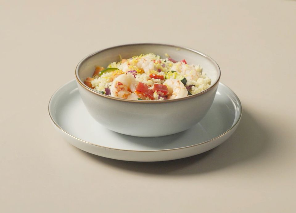Cuscús con gambas y verduras coloridas servido en un plato de cerámica crema