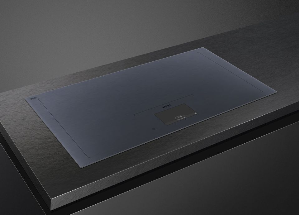 A black cooktop with a pan on top. A hand shows the lack of heat on the unused zones.