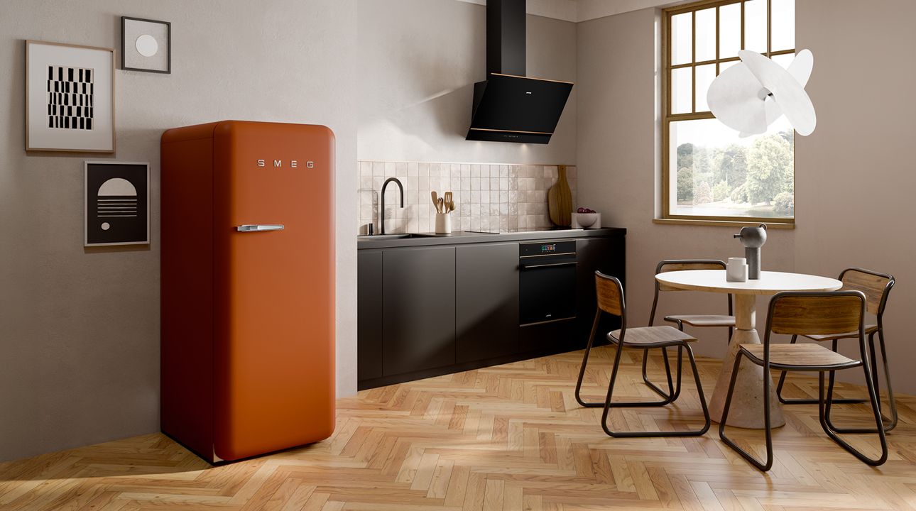 Minimalist kitchen with SMEG appliances in amber clay finish, including a range cooker, extractor hood, and retro-style refrigerator, set against light wood cabinetry, soft neutral walls, and natural light from a large window.