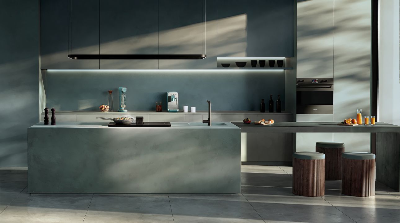 Bright contemporary kitchen featuring SMEG appliances in matt moonlight finish, including a range cooker, extractor hood, and retro-style refrigerator, set within green cabinetry, warm wood accents, and a large dining table under natural light.