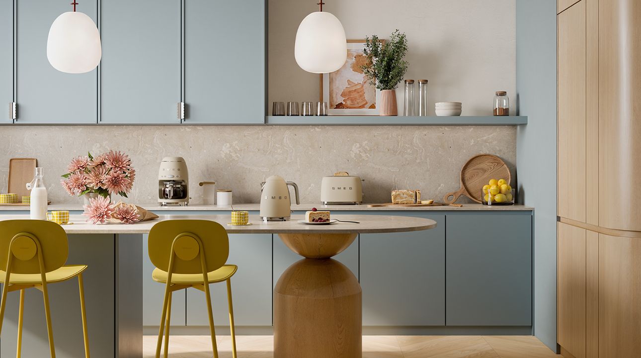 Modern kitchen interior featuring SMEG appliances with storm blue accents, including a cooker, extractor hood, and retro-style refrigerator, set against neutral cabinetry with natural light, plants, and a dining area.