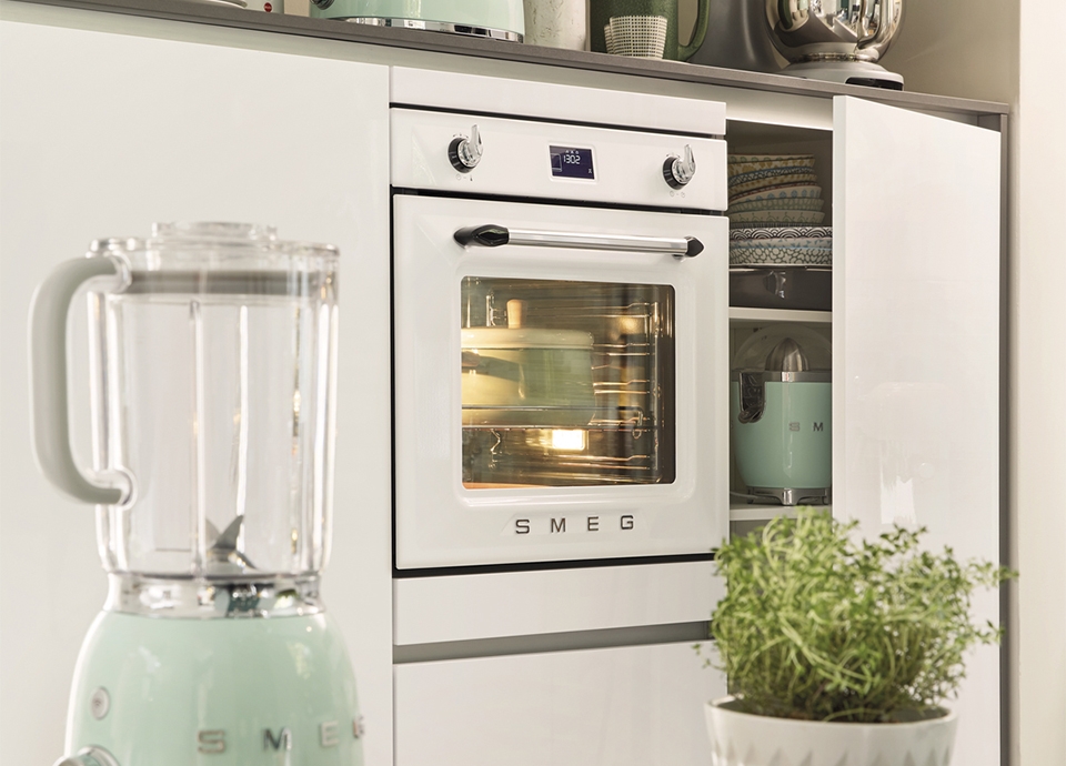 A white, retro style kitchen featuring Smeg's 50's style single oven, integrated into white kitchen units.