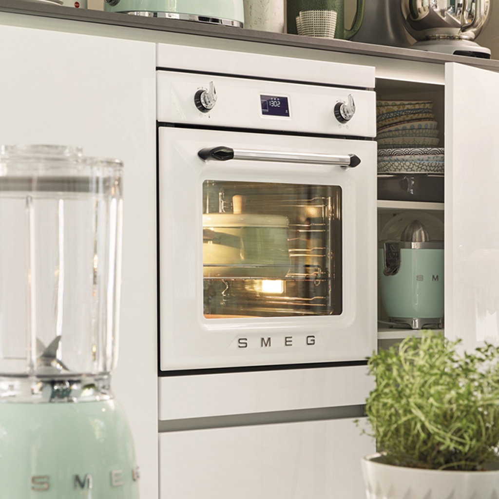 A white, retro style kitchen featuring Smeg's 50's style single oven, integrated into white kitchen units.