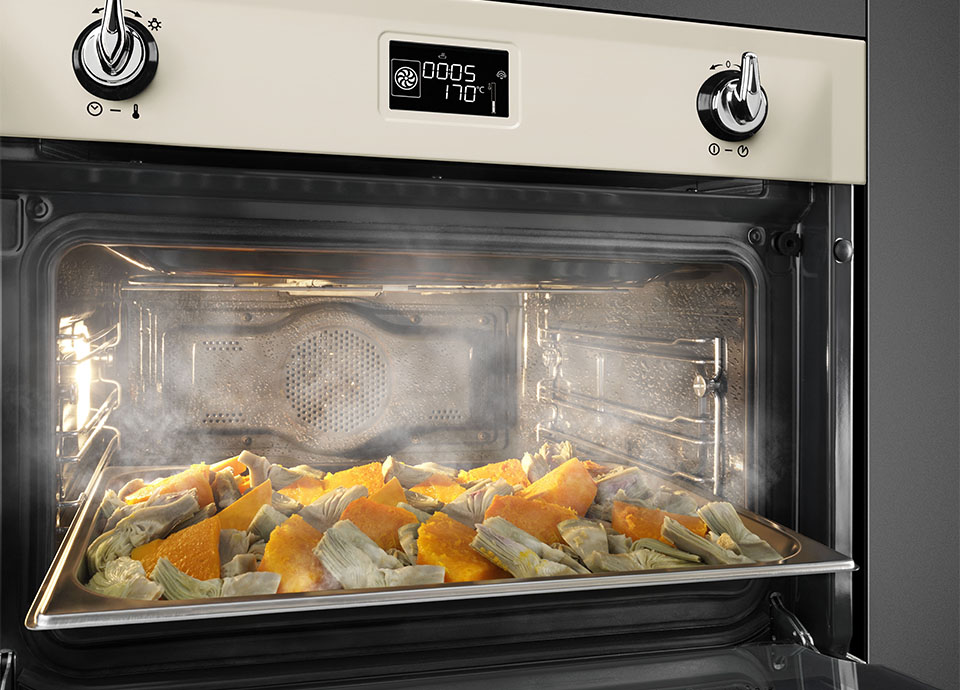 A steam oven with a tray of chunky cut vegetables being steamed