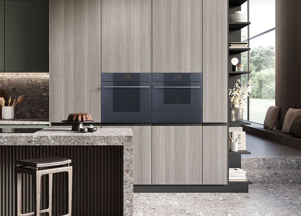 A contemporary kitchen with modern grey, handle-less units, and two of Smeg's built-in single ovens in a column arrangement