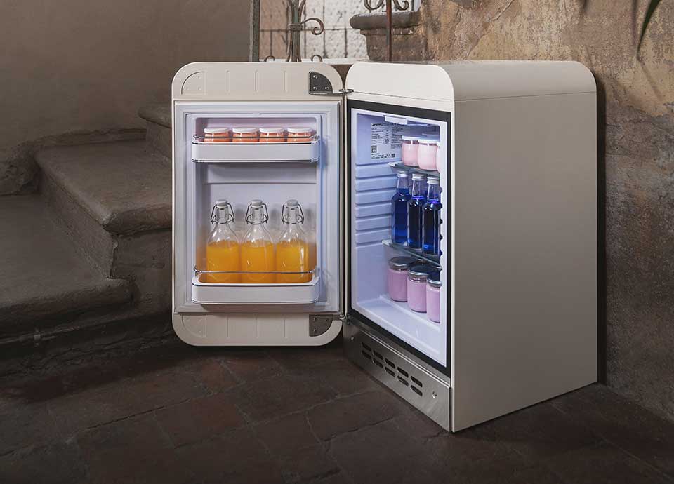 A small drinks fridge housing an number of bottles of orange juice and more.