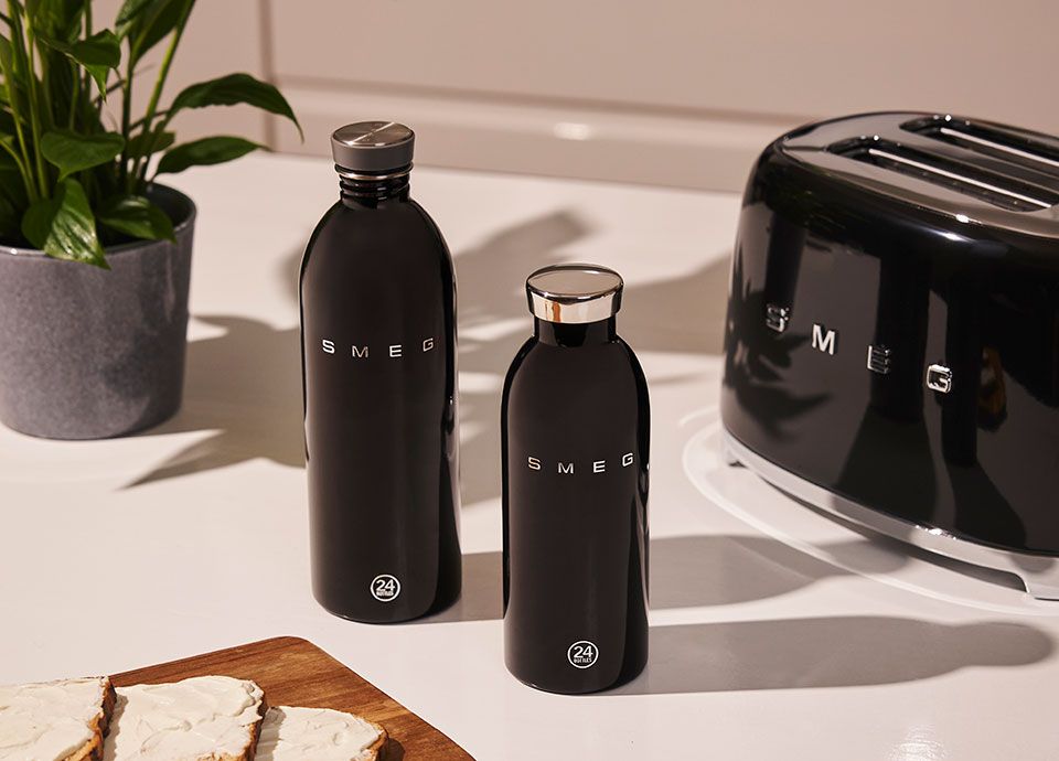 Two black Smeg water bottles, a 1-litre and a 500-ml bottle, on a kitchen counter next to a black Smeg toaster