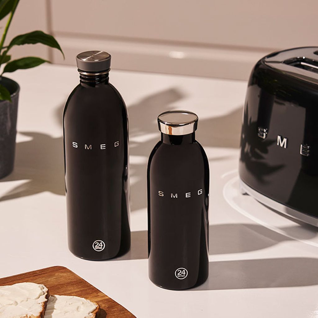 Two black Smeg water bottles, a 1-litre and a 500-ml bottle, on a kitchen counter next to a black Smeg toaster