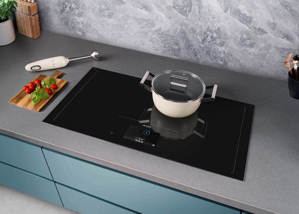 A black Induction hob with a cream cookware dish on top