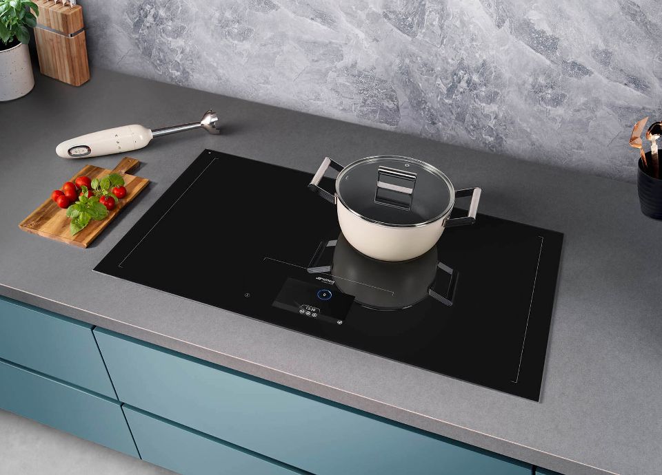 A black Induction cooktop with a cream cookware dish on top