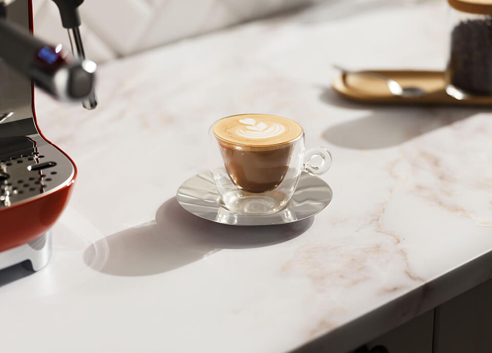 Flat white served in a clear glass, topped with smooth, velvety foam