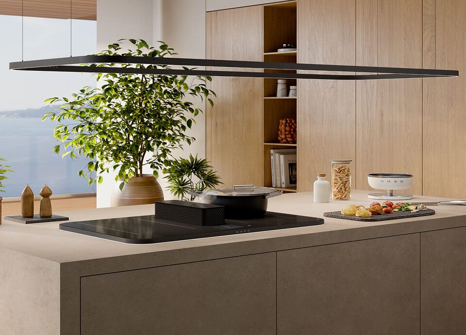 Minimalist suspended lighting track positioned above a modern kitchen island, paired with an induction hob and integrated hood