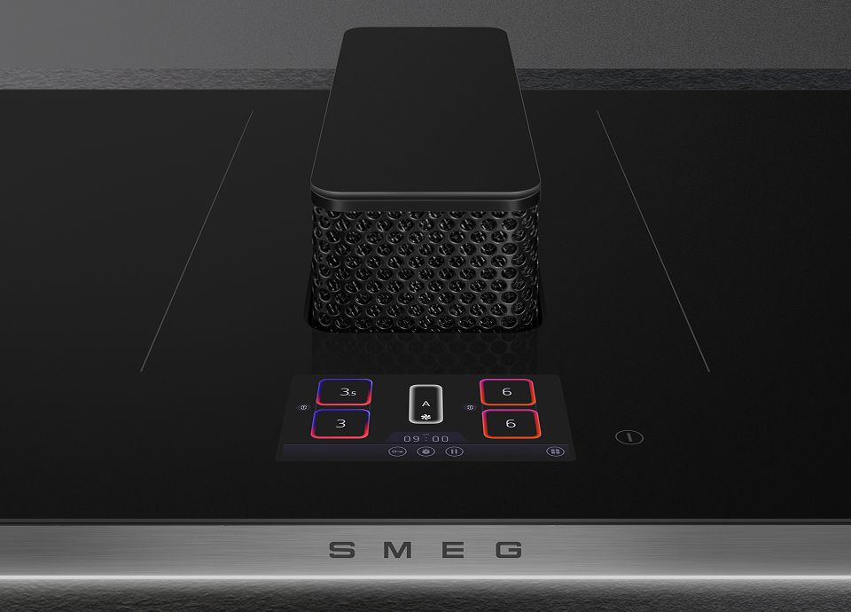 The image shows a closeup of the TFT colour display with the downdraft hood in the background on a SMEG Isola hob