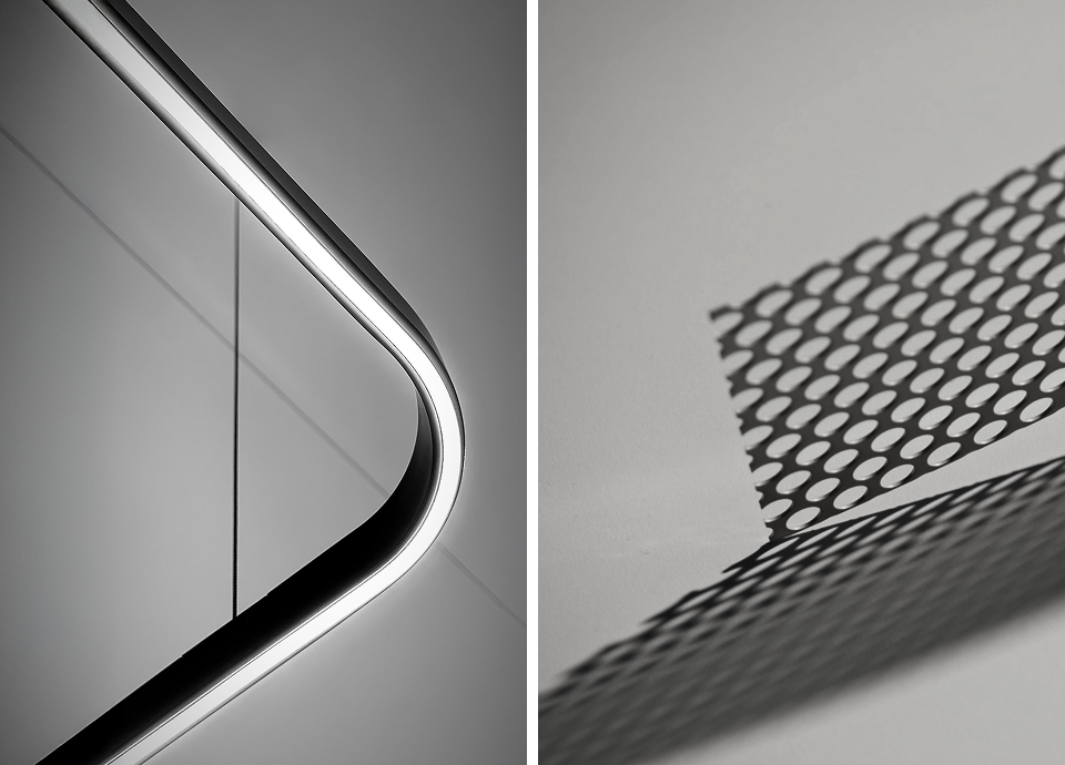 Macro photography of minimalist design details: a curved integrated LED light strip on a matte surface and a perforated metal grid casting geometric shadows.