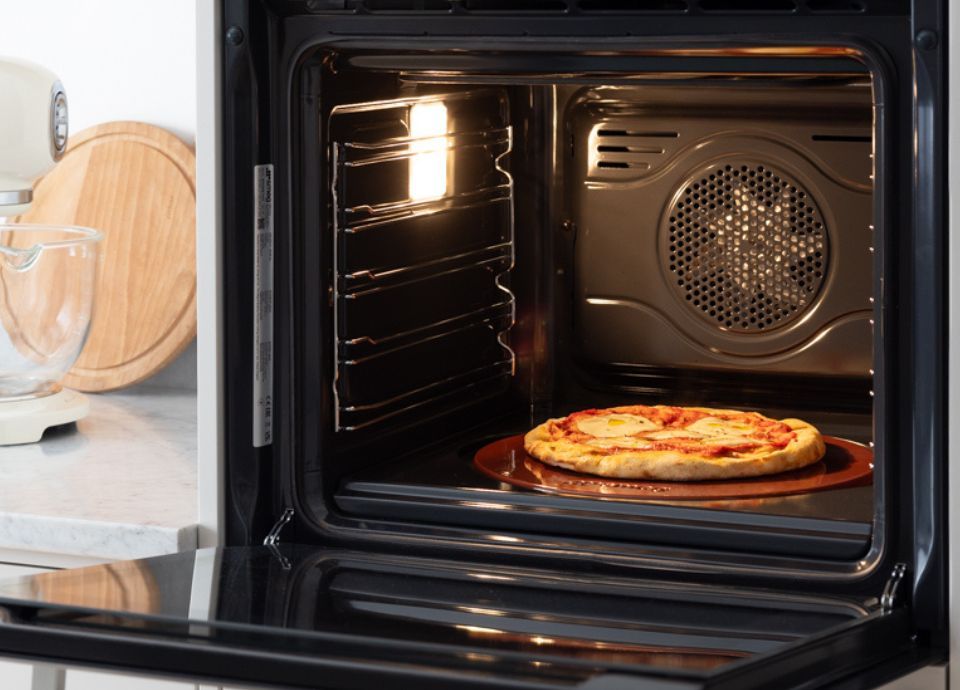 The image shows a pizza perfectly baked inside of a Smeg oven.