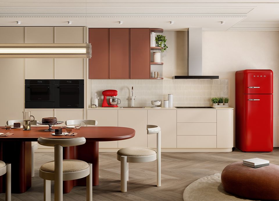 Modern kitchen with beige and terracotta cabinets, a red retro fridge, and a matching dining table with soft upholstered chairs.