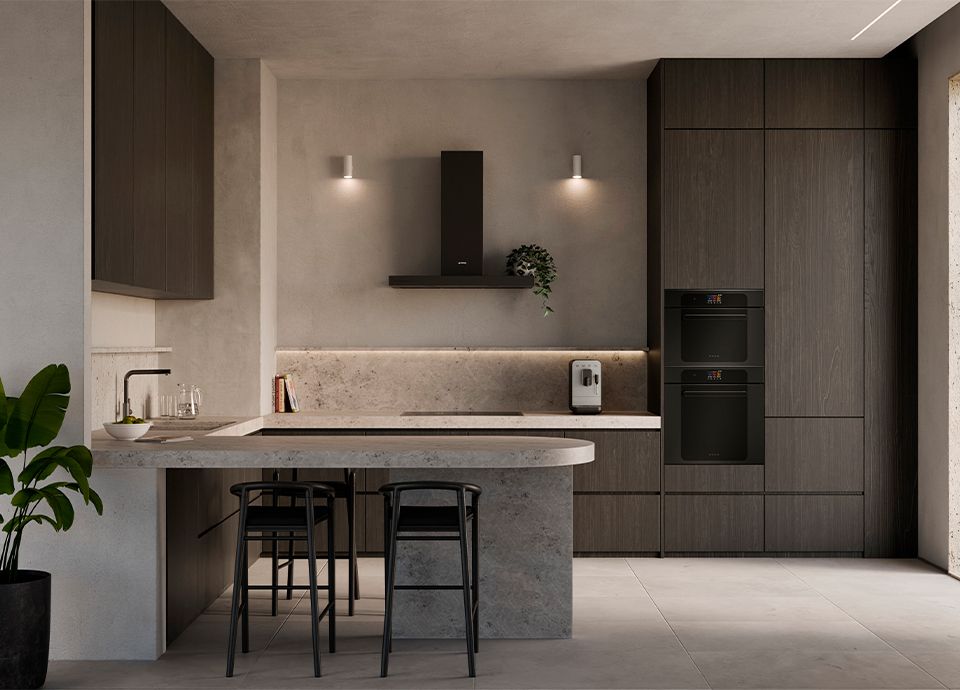 A modern kitchen with a gray stone isola and backsplash paired with dark wood cabinets. Two black glass Musa appliances are stacked in the wall, with a simple black range hood on the far wall.