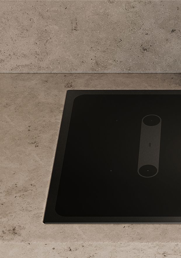Induction hob with smooth black glass surface on a concrete kitchen worktop.