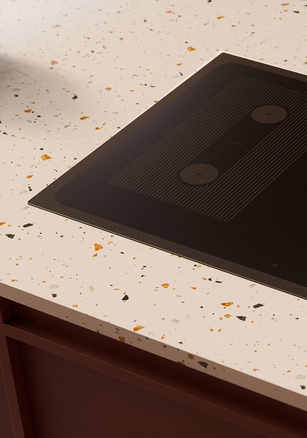 Close up of a black induction hob on a marble kitchen countertop