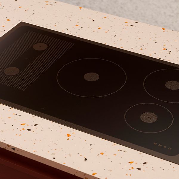 Black glass induction hob with integrated downdraft extractor, featuring two cooking zones, set into a stone countertop.