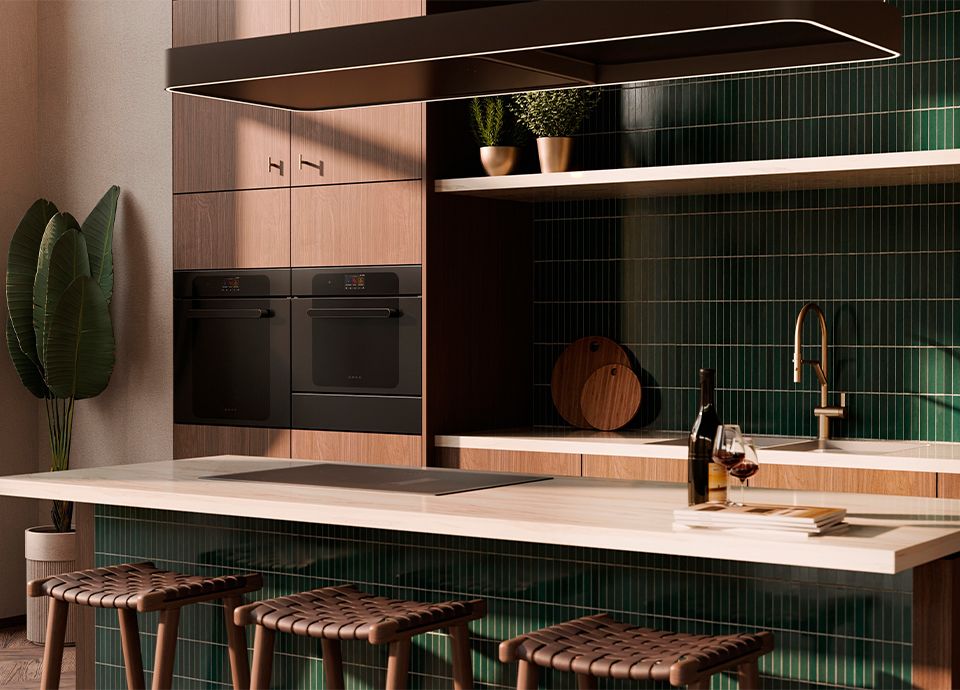 A kitchen featuring wood cabinets, black built-in ovens, and a white marble island with green vertical tiles and woven leather stools.