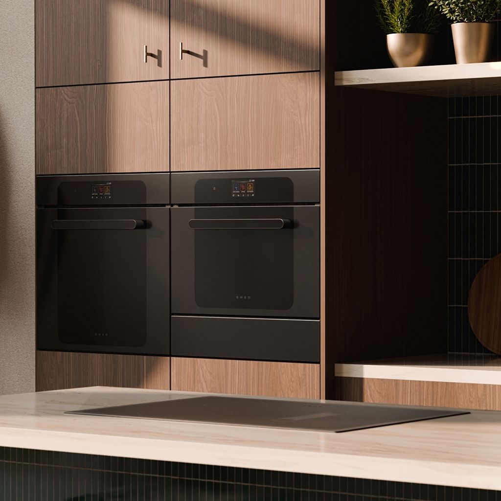 Side-view of a modern kitchen featuring wood cabinetry with black built-in ovens and dark green vertical tiled.