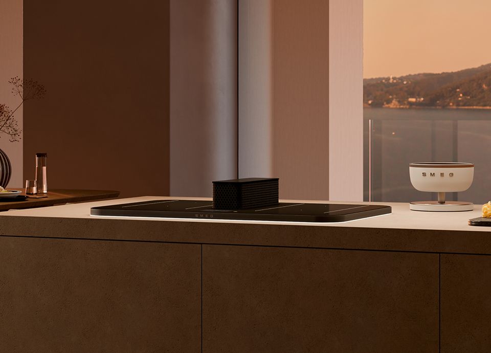 Modern kitchen with a sleek induction cooktop integrated into a central island, paired with a minimalist suspended extractor hood above, surrounded by wooden cabinetry, open shelving with kitchen accessories, and a built-in wine cooler.