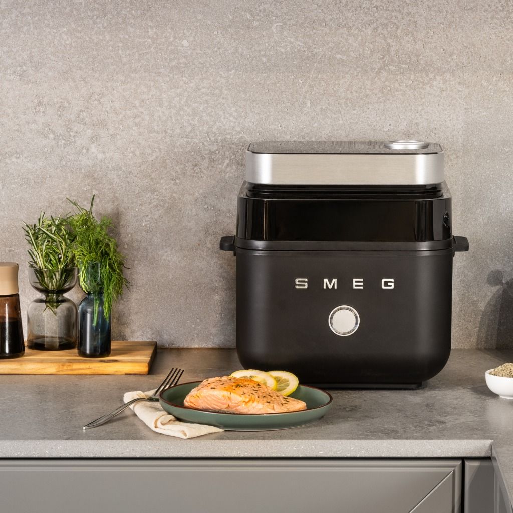 Friggitrice ad aria da banco SMEG con finitura nero opaco e pietanza preparata sul piano di lavoro della cucina.