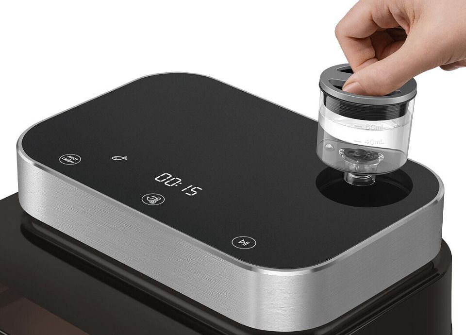 Smeg air fryer with removable water tank being inserted on top