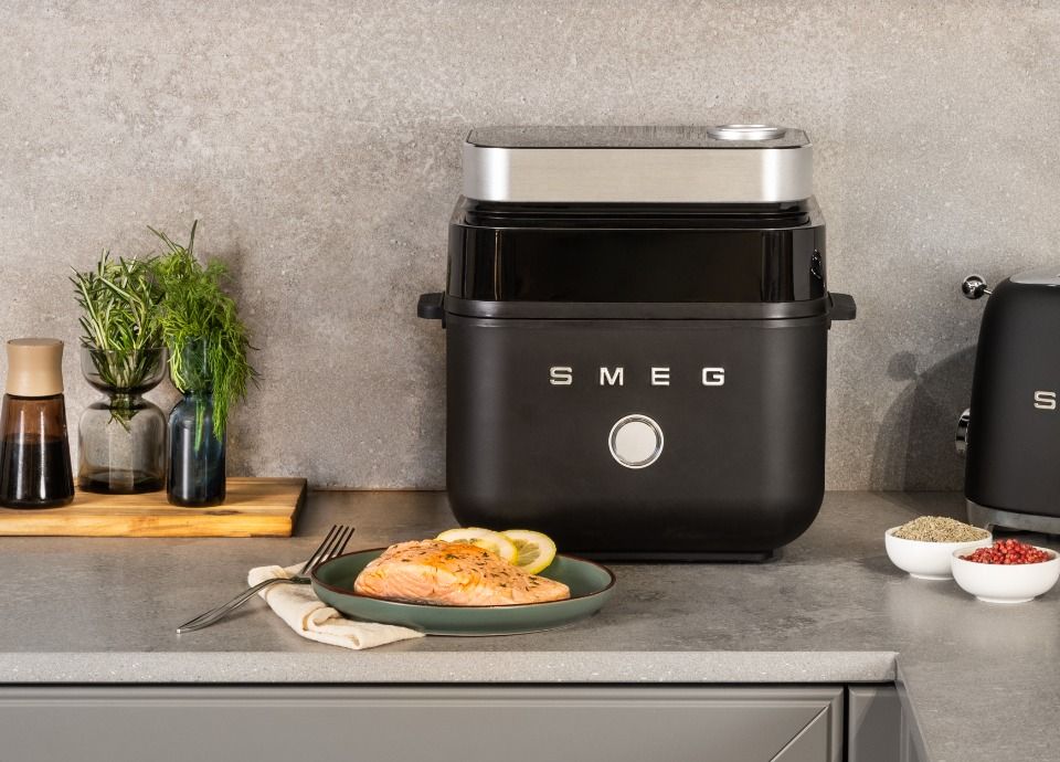 SMEG air fryer in black finish styled with gourmet salmon and herbs in a contemporary kitchen