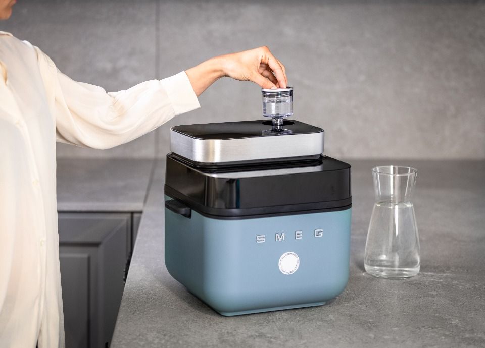 Smeg air fryer with user inserting water tank on top for controlled humidity cooking