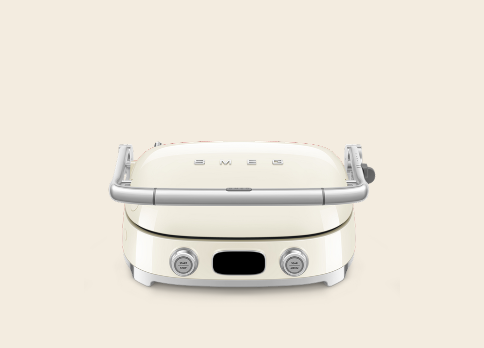 Wielofunkcyjny grill Smeg w kremowym wykończeniu przygotowujący burgery na nowoczesnej wyspie kuchennej.