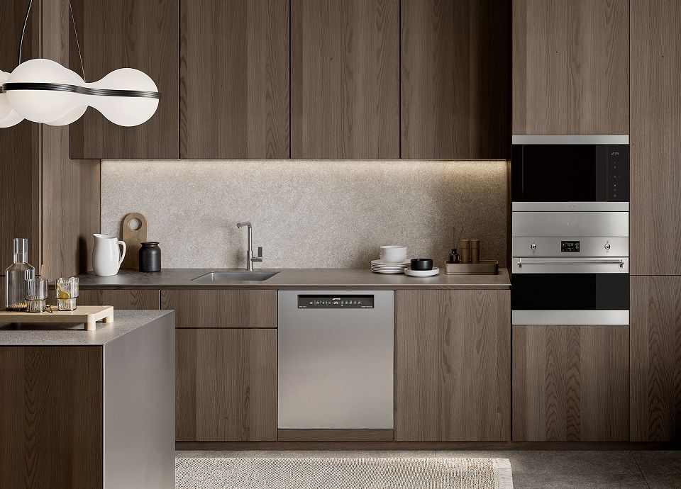 A warm, modern kitchen with wood cabinetry featuring an eye-level Smeg microwave and a stainless dishwasher.